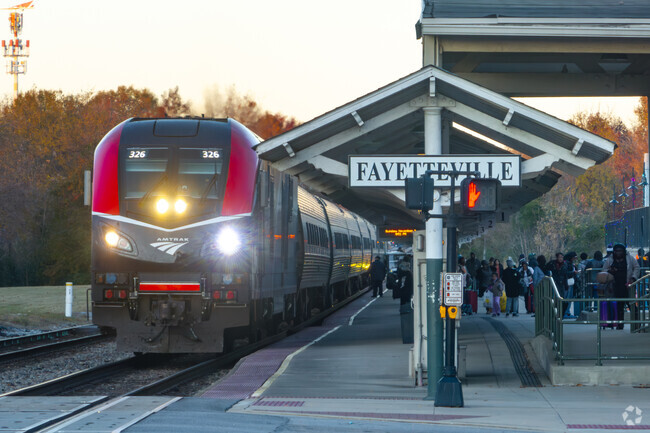 Passengers wait on shaded benches at the Fayetteville Amtrak station depot near Spout Springs.