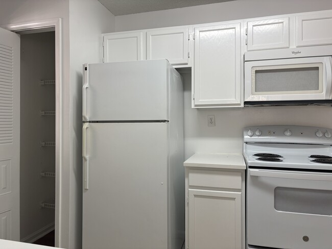 view to pantry, fridge, stove, and microwave