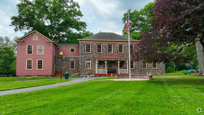 The exterior buildings at The Village Charter School are surrounded by lush lawns and trees.
