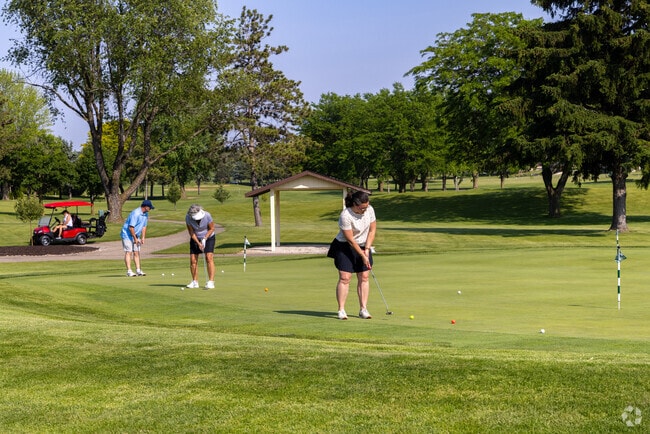 Locals practice putts under blue skies at Evergreen Golf Club.