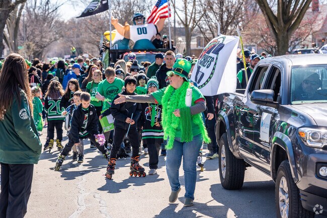A woman tosses a necklace to some kids at the annual Elmhurst St. Patrick's Day Parade.