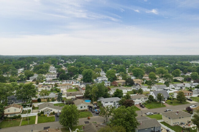 Houses in Selden are nestled under the canopy of lush trees.