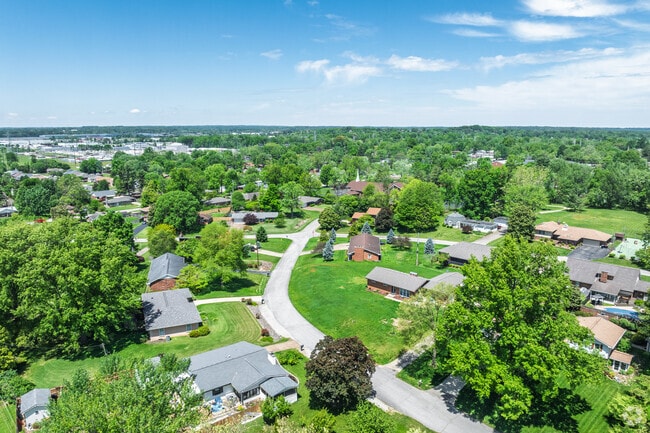 Dense trees fill Melody Hill's rolling landscape, broken up by grassy lawns and homes.