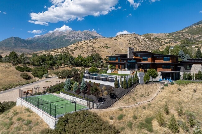 A mansion with wood details and a tennis court in Rock Canyon.