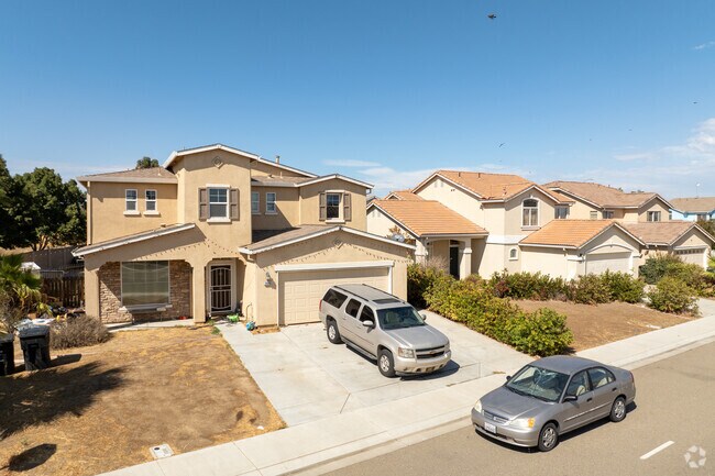 Spanish-style homes with driveways and large front lawns line Santa Nella's residential streets.