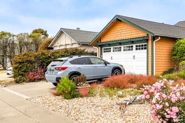 Find gravel lawn with colorful flora flanking even more colorful homes in El Granada,