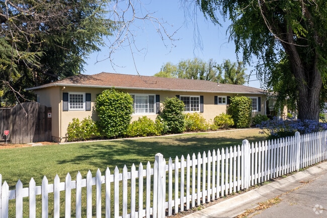 Ranch-style homes in Quito Village with a white picket fence.