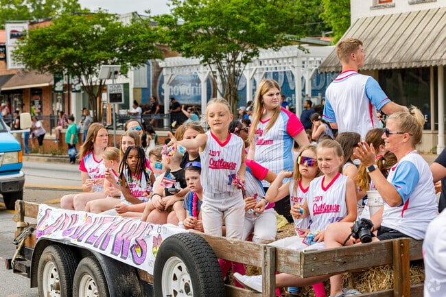 The local Lady Outlaws softball team throws candy to the parade onlookers on Locust Grove Day.