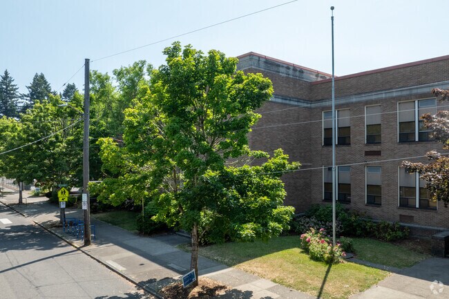 Mature trees shade the front of Llewellyn Elementary on SE 14th Ave in Portland.