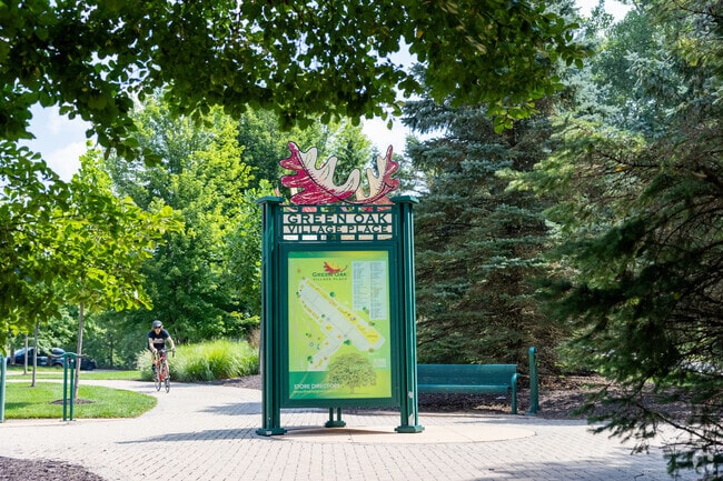 A bicyclist enjoys open green space and fresh air at Green Oak Village Place.