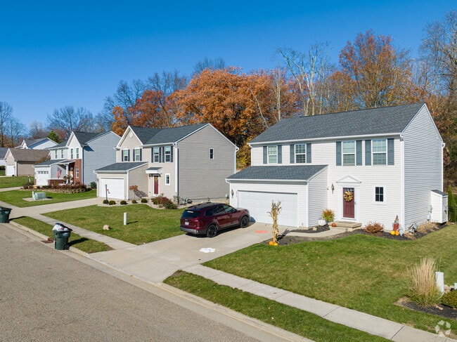 New two-story homes with well manicured lawns and backed up by large trees in New England.