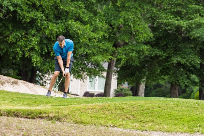 A golfer lines up his shot near a sand trap on Arcadian Shores’ scenic fairways.