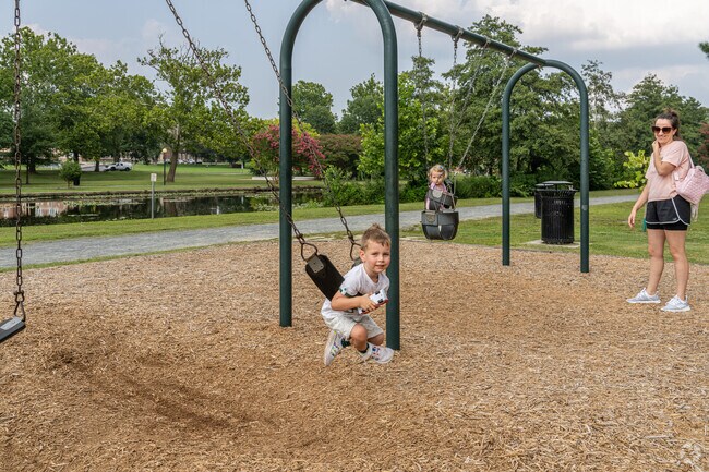 A curious young boy plays on the swings with his little sister at Salisbury City Park.