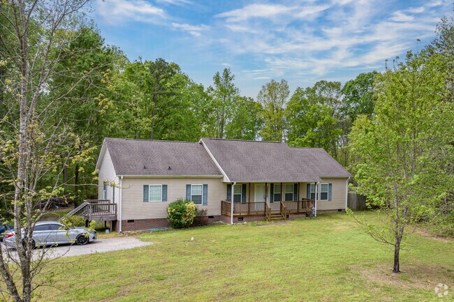 A side-gabled ranch home is nestled under mature trees in Ritters Lake.