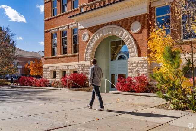 Student pauses near a historic building at Snow College.