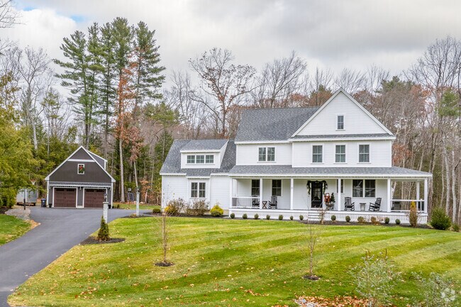 This spacious colonial-style home features a large front porch and a detached garage, set on a beautifully landscaped lot.