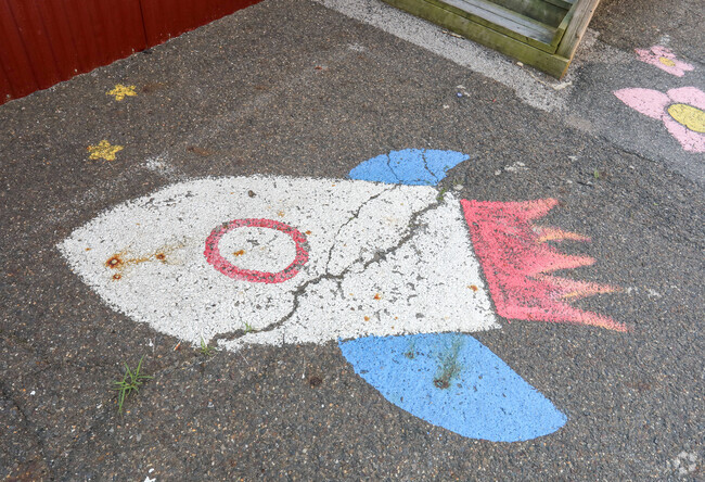 A chalk mural of a rocket ship adorns the sidewalk of Harrison Elementary School.