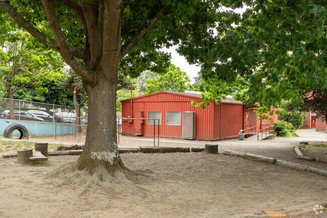 A brick red building and this shady outdoor spot adds class space   behind Sabin Elementary.