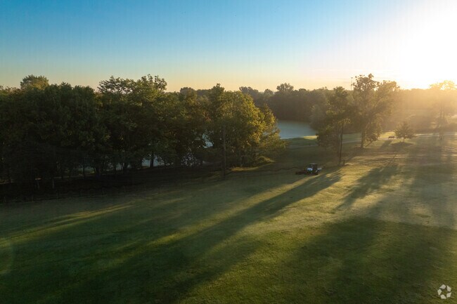 The sun rises over a worker grooming the course for a Park DeVille golfer.