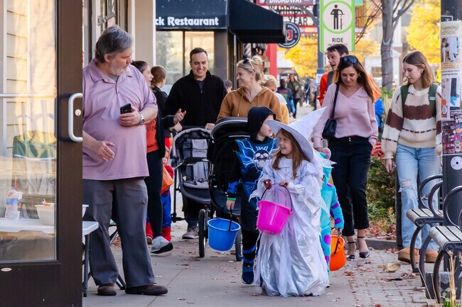 Families in Halloween costumes gather candy from local businesses at Treat Fest.