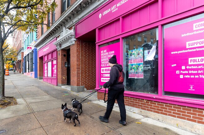 A local resident walks past the vibrant Punto Urban Art Museum in The Point, Massachusetts — a community-driven project using public art to bridge cultural and socioeconomic divides.
