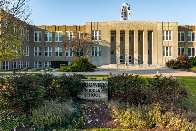 The small sign for Sedgwick Middle School is hidden behind overgrown bushes.