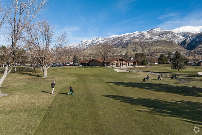 Golfers play at Davis Park Golf Course with views of snow-capped mountains in Fruit Heights.