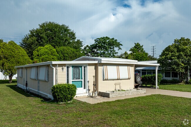 Mid-century manufactured home in Zephyrhills South includes storm shutters and carport.