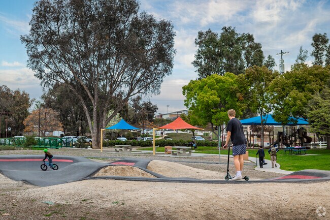 Teens ride bikes and scooters on the pump track at Ronald Reagan Park near Rancho Highlands.