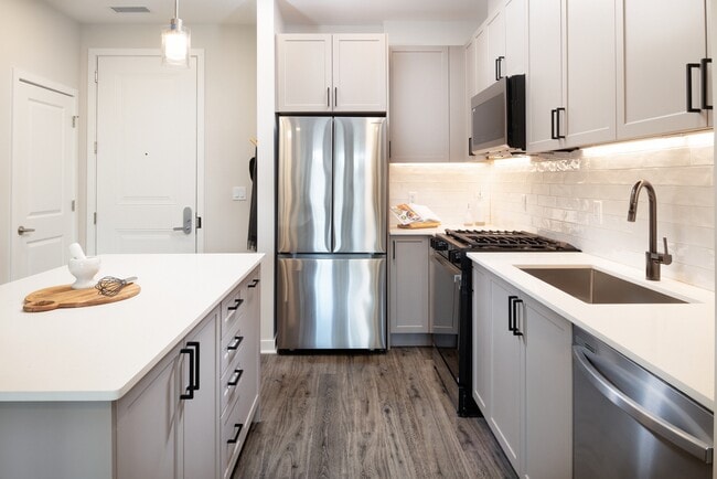 Modern with grey cabinetry, white quartz countertops, white tile backsplash, and stainless-steel appliances