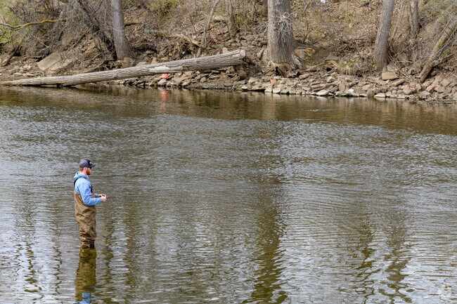 A man enjoys fishing in the Red Cedar River along River Point Park in Reo Town.