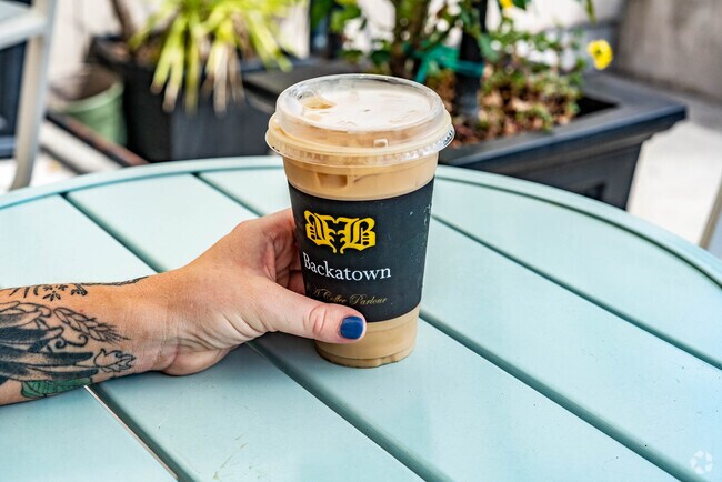 A person holding their iced latte on the patio of Backatown Coffee in the Iberville neighborhood.