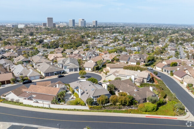 An aerial view of Broadmoor Sea View showcases its stunning homes and ocean views, with downtown Newport Beach creating a vibrant backdrop to this exclusive coastal neighborhood.