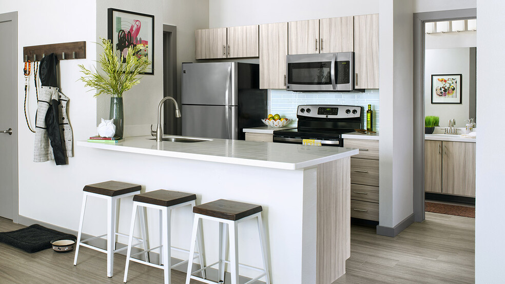 Apartment Kitchen with Stainless Steel Appliances, quartz counters and wood-like floors.