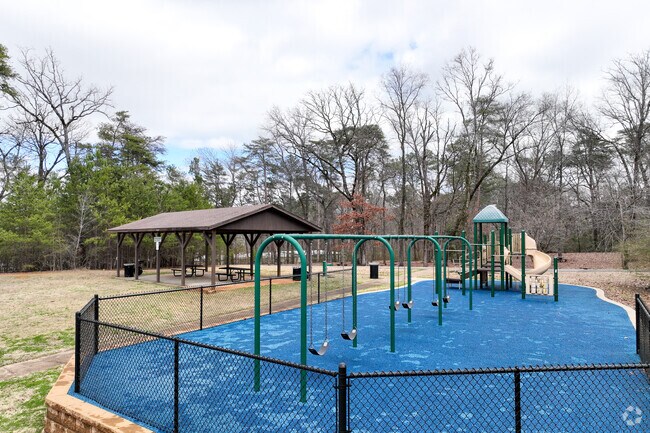 The playground area at Garden Highlands Park has blue flooring near the field and picnic area.