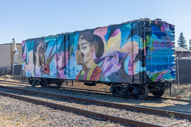 A train car sits unused by the tracks in McPherson, repurposed as a beautiful mural.
