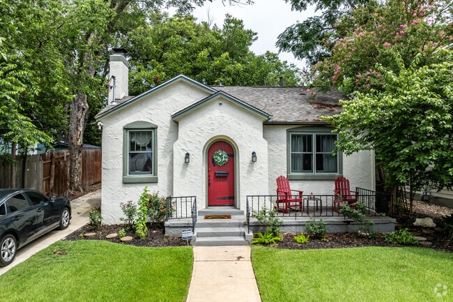This cute bungalow really stands out with stucco siding and a red door in Old Enfield.