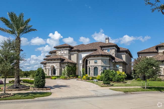 A beautiful Riverstone Mediterranean style mansion sits atop a well maintained lawn.