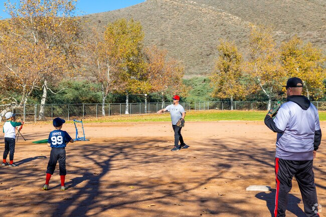 A father and sons bond over a game of catch, practicing their skills in Sun City.