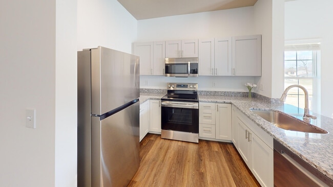 The Jane kitchen opens to the living room, and features granite countertops and stainless steel appliances, including a microwave and dishwasher.