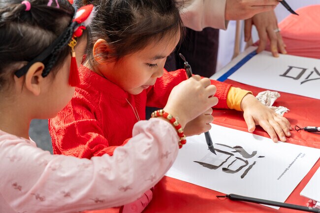 Children try their hand at traditional calligraphy, carefully drawing Chinese characters during the Lunar New Year event in Alhambra.