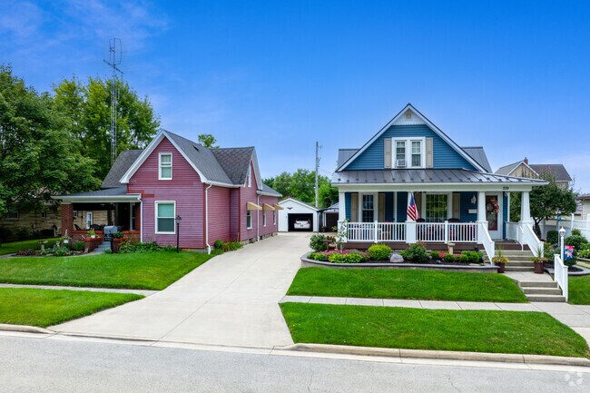 A residential street in Coldwater, Ohio shows colorful homes and a sloped sidewalk.