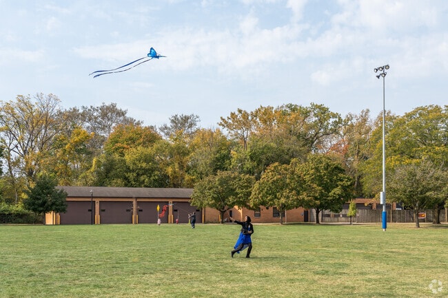 A woman runs across the grass flying a kite during Family Kite Day near Ballard Terrace.