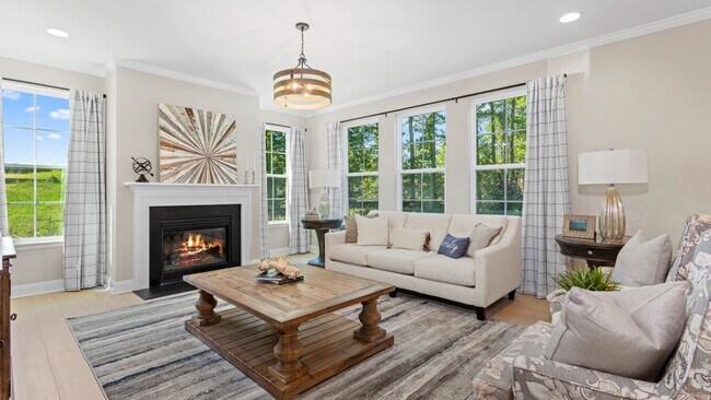 Family room with fireplace and large windows in a DRB Homes Drayton model home in the Neill's Pointe community.