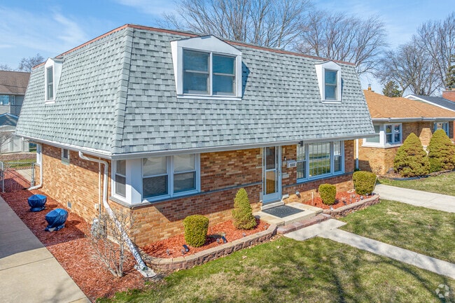 A Dutch Colonial-inspired Westchester home features a neatly manicured front lawn.