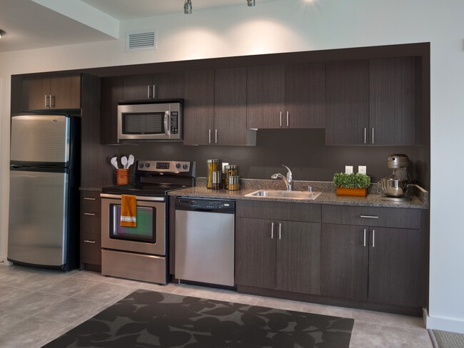 Classic Package I kitchen with brown speckled granite countertops, espresso cabinetry, stainless steel appliances, and hard surface flooring