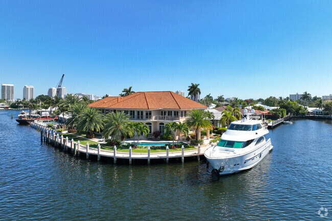 Beautiful waterfront Mediterranean-style home with a large yacht docked outside.