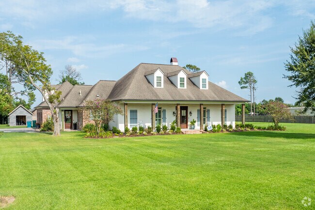 A larger acadian style home proudly sits on a manicured lawn in Prien.
