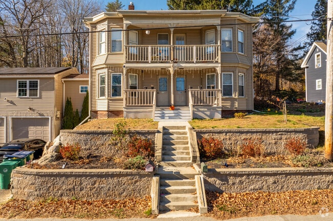 A multifamily home in West Fitchburg is situated above the street with steps leading to it.