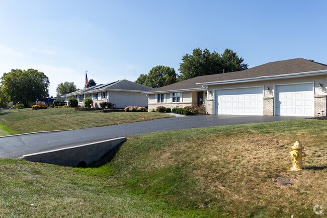A peaceful suburban scene in Cherry Valley, featuring single-story homes with manicured lawns and vibrant greenery under a clear blue sky.